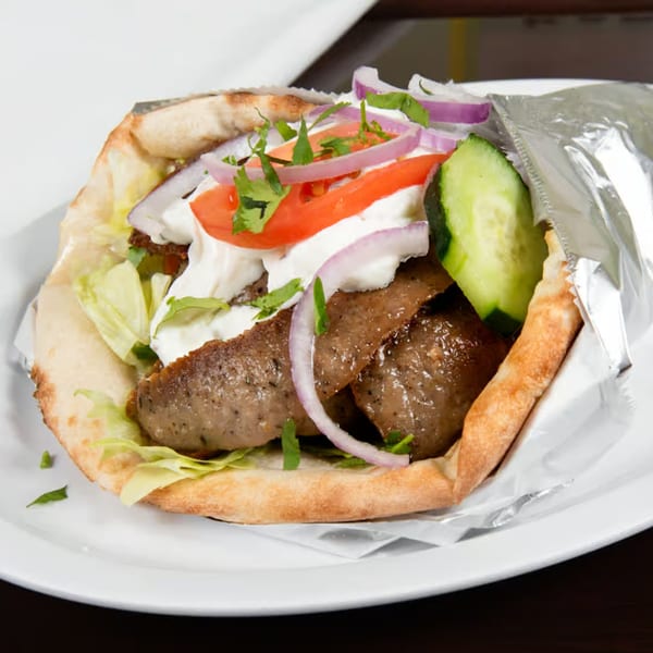 Z Kabob's gyro sandwich with meat, lettuce, tomatoes, onions, cucumbers, and white sauce in pita bread.