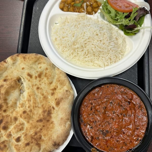 A Z Kabob meal with rice, chickpeas, salad, naan bread, and a side of curry.