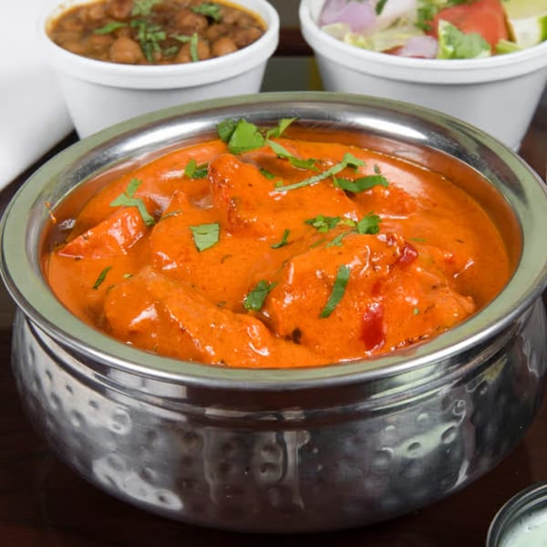 Z Kabob's chicken tikka masala in a hammered metal bowl, with sides of chickpeas and salad.