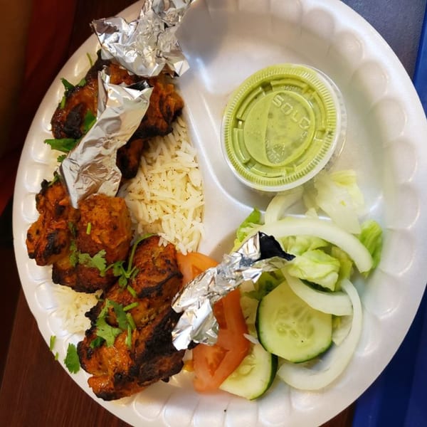 Z Kabob's chicken kebab plate with rice, salad, and green sauce on a white plate.